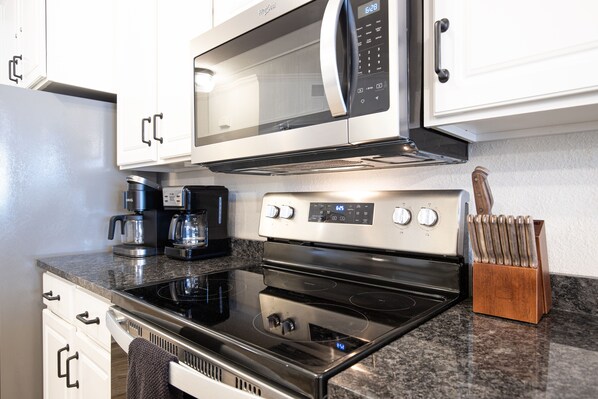 A kitchen with a stainless steel stove, microwave, and coffee maker.