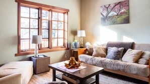 Una sala de estar acogedora con un sofá, una mesita de centro y una ventana con persianas de madera.