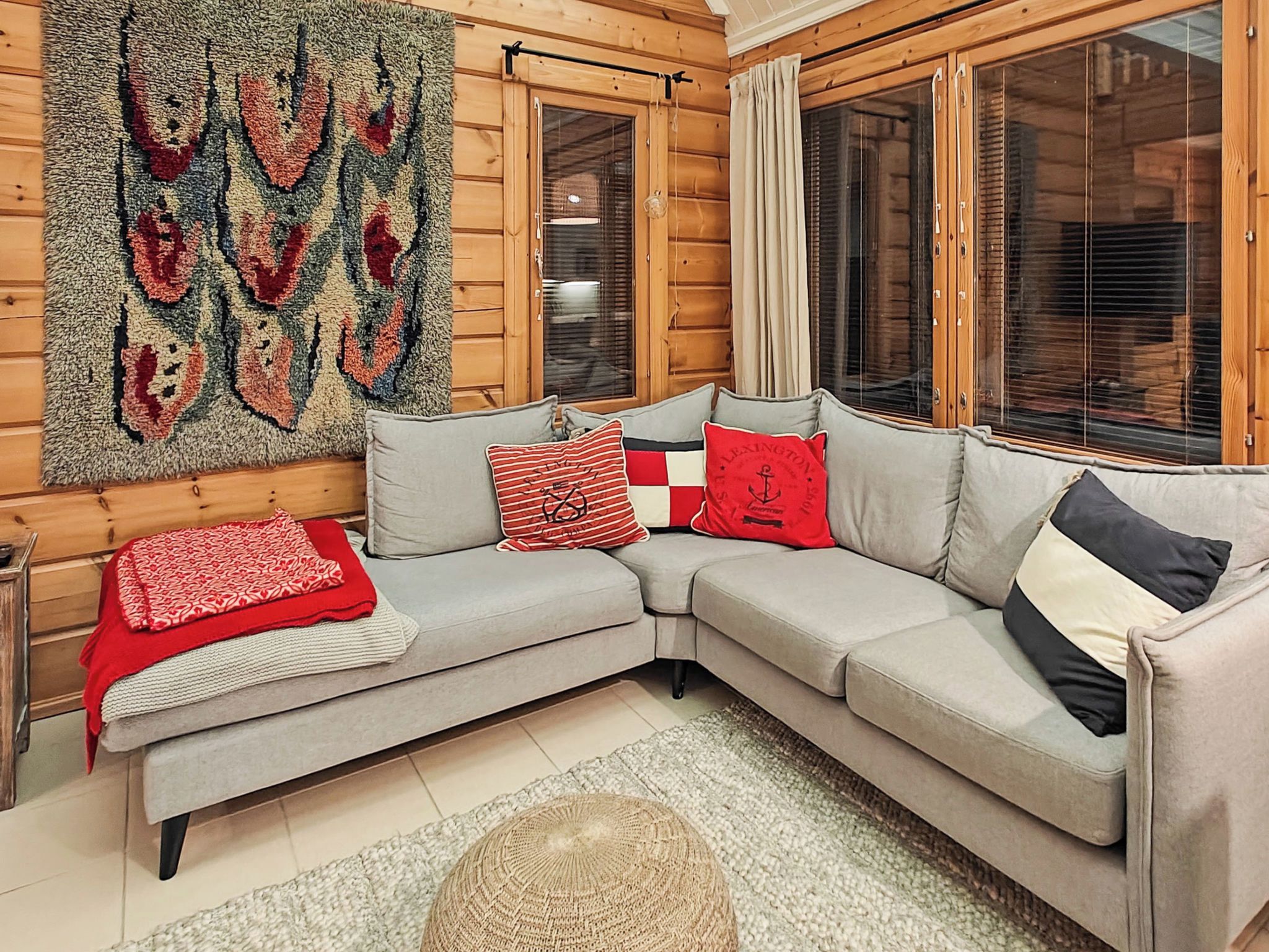 A cozy living room with a grey sectional sofa, a large wall rug, and a wooden floor.
