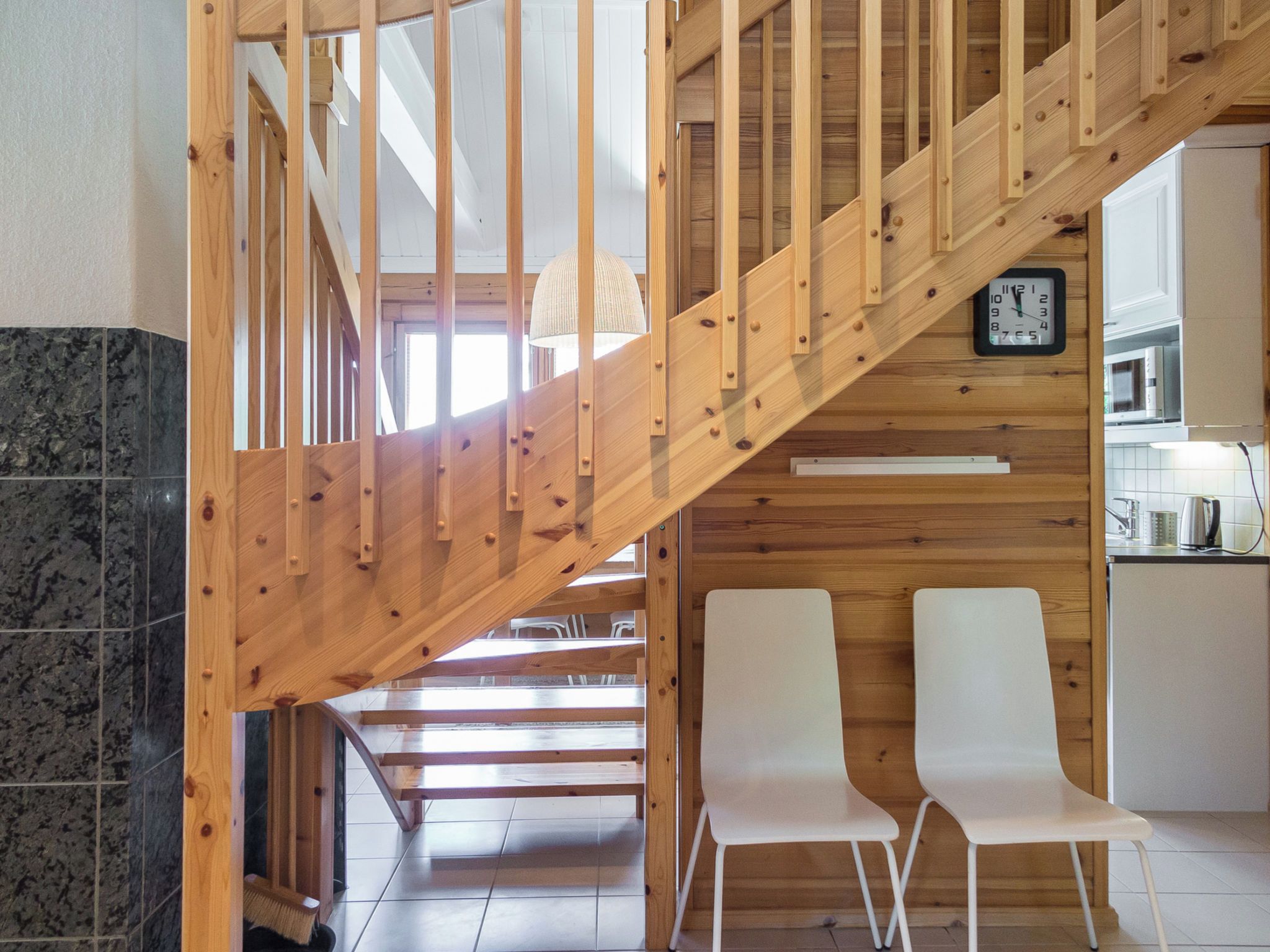 Una escalera de madera conduce a un segundo piso, con un área de cocina visible a la derecha.