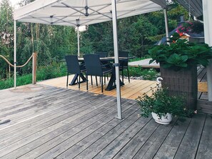 An outdoor patio with a wooden deck, a covered seating area with chairs and a table, and a potted plant. - Tinttityy by Interhome (Nilsiä)