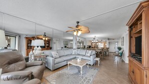 A spacious living room with a sectional sofa, a coffee table, and a dining area with chairs and a table. - Remodeled Beachfront beauty! Inlet Reef 416 (Destin)
