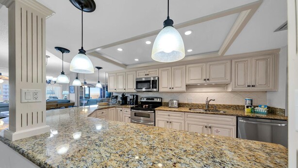 A modern kitchen with granite countertops, stainless steel appliances, and pendant lighting. - Remodeled Beachfront beauty! Inlet Reef 416 (Destin)