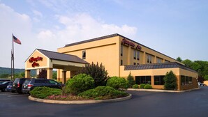 Un Hampton Inn amb façana groga, zona de pàrquing coberta i entrada enjardinada.