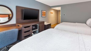 Habitació d'hotel amb un llit, un escriptori amb una cadira, una televisió i un microones.