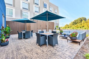An outdoor patio with tables and chairs, umbrellas, and potted plants. - Hampton Inn Danville, VA (Danville)