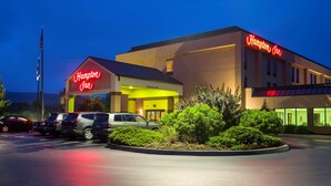 Un hotel Hampton Inn amb un cartell de làmines, un aparcament i una entrada ben il·luminada.