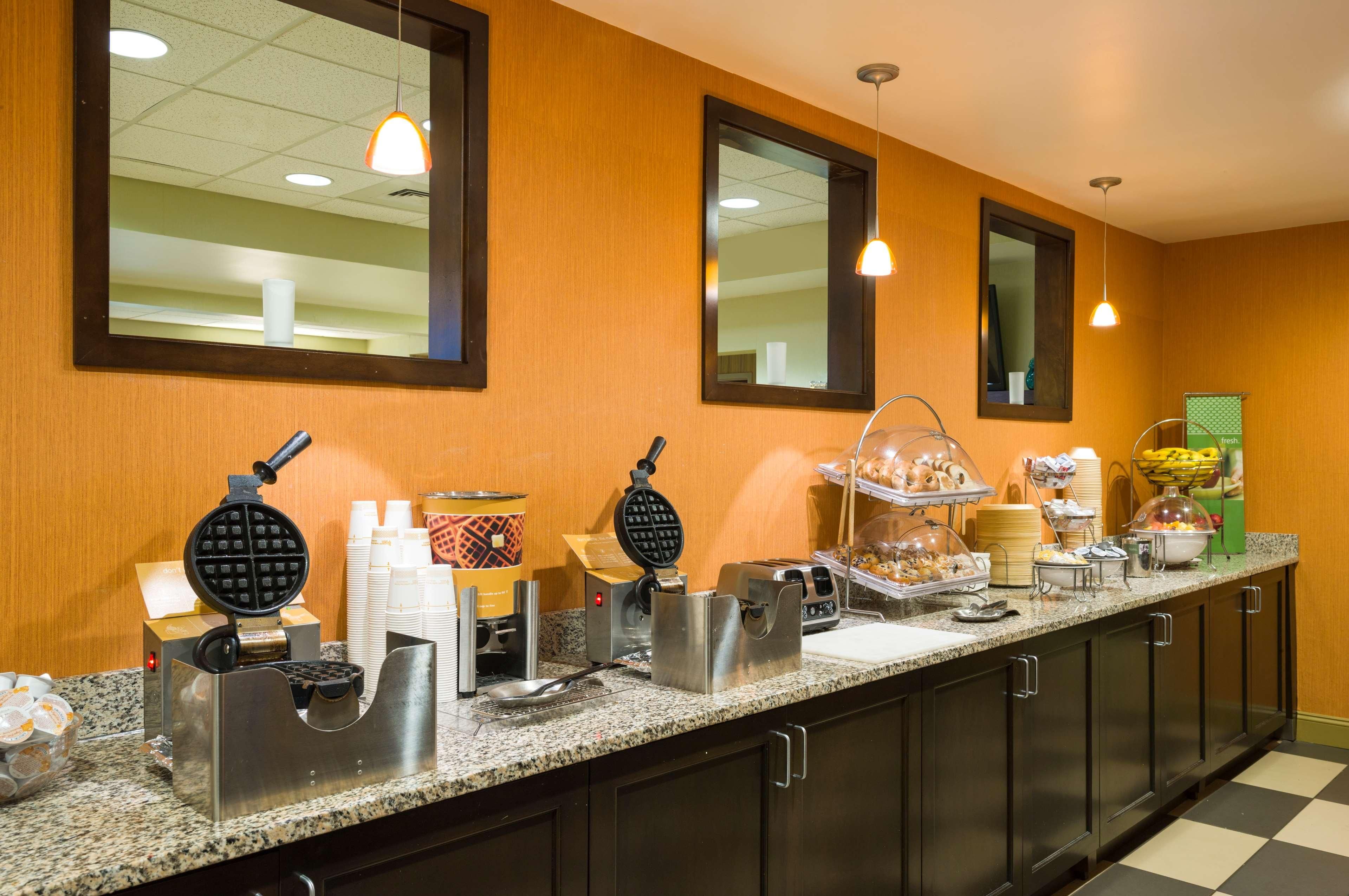 A buffet setup with waffle irons, coffee makers, and various food items.