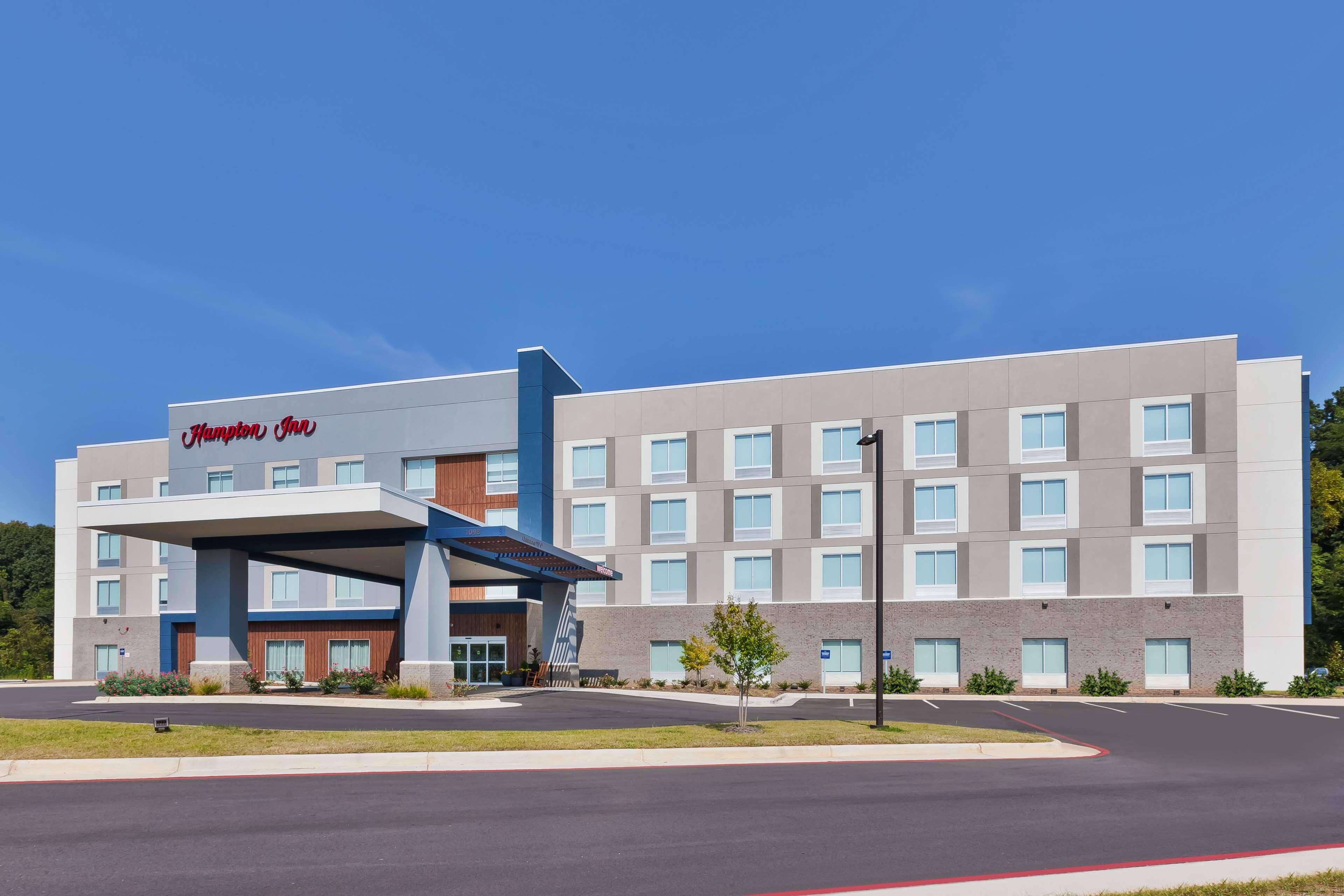 A modern hotel with a covered entrance, multiple floors, and a clear sky.