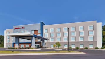 A modern hotel with a covered entrance, multiple floors, and a clear sky.