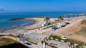 A coastal road with a beach on one side and a parking lot with cars. - Blue Sea by Interhome (Cunit)