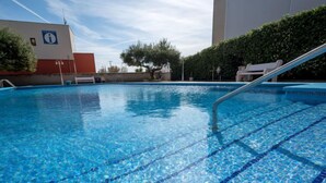 A clear blue swimming pool with tiled edges, surrounded by a low wall and a hedge. - Blue Sea by Interhome (Cunit)