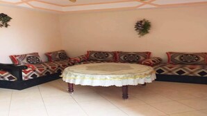 Una habitación con un conjunto de sofás, una mesa redonda con mantel de encaje y un techo decorativo.