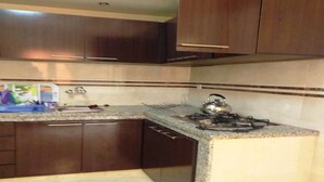 Una cocina con armarios de madera oscura, encimera de granito y estufa a gas.