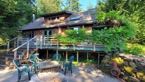 Eine Holzhütte mit einer Terrasse, Sitzgelegenheiten im Freien und einer Steinmauer.