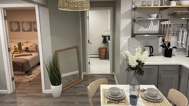Una cocina moderna con comedor, con una mesa blanca dispuesta con platos, tazones y un florero.