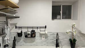 Una cocina moderna con un lavamanos de acero inoxidable, utensilios de cocina negros colgantes, un escurreplatos negro y una orquídea en maceta.
