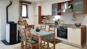 A modern kitchen with a dining area, featuring a stove, oven, and a built-in dishwasher.