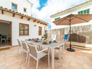 Un patio con una mesa lista para el desayuno, asientos exteriores y un paraguas grande.