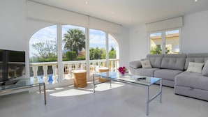 Un salon moderne avec un canapé, une table basse en verre et un téléviseur.
