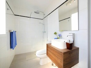 Enjoy a refreshing shower in the sleek shower enclosure with handheld showerhead and glass door, accompanied by a convenient vanity with sink and mirror.