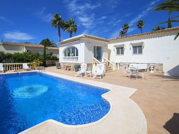 Relax by the serene pool surrounded by palm trees and comfortable lounge chairs.