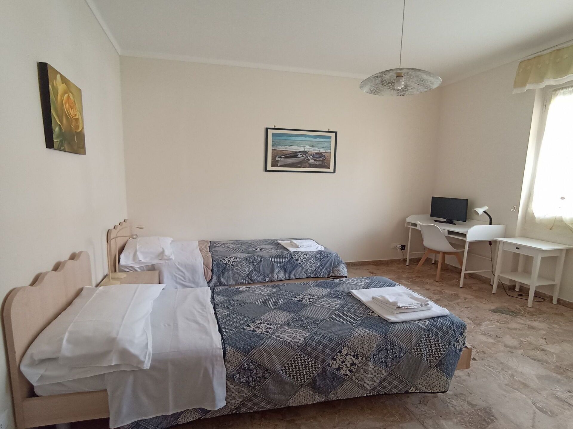 Un dormitorio con dos camas, un escritorio, una silla, un televisor y un cuadro en la pared.