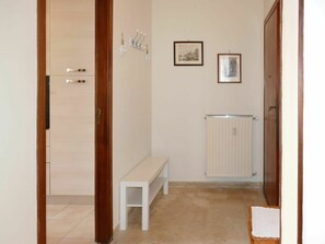A narrow hallway with a bench, a radiator, and two framed pictures on the wall.
