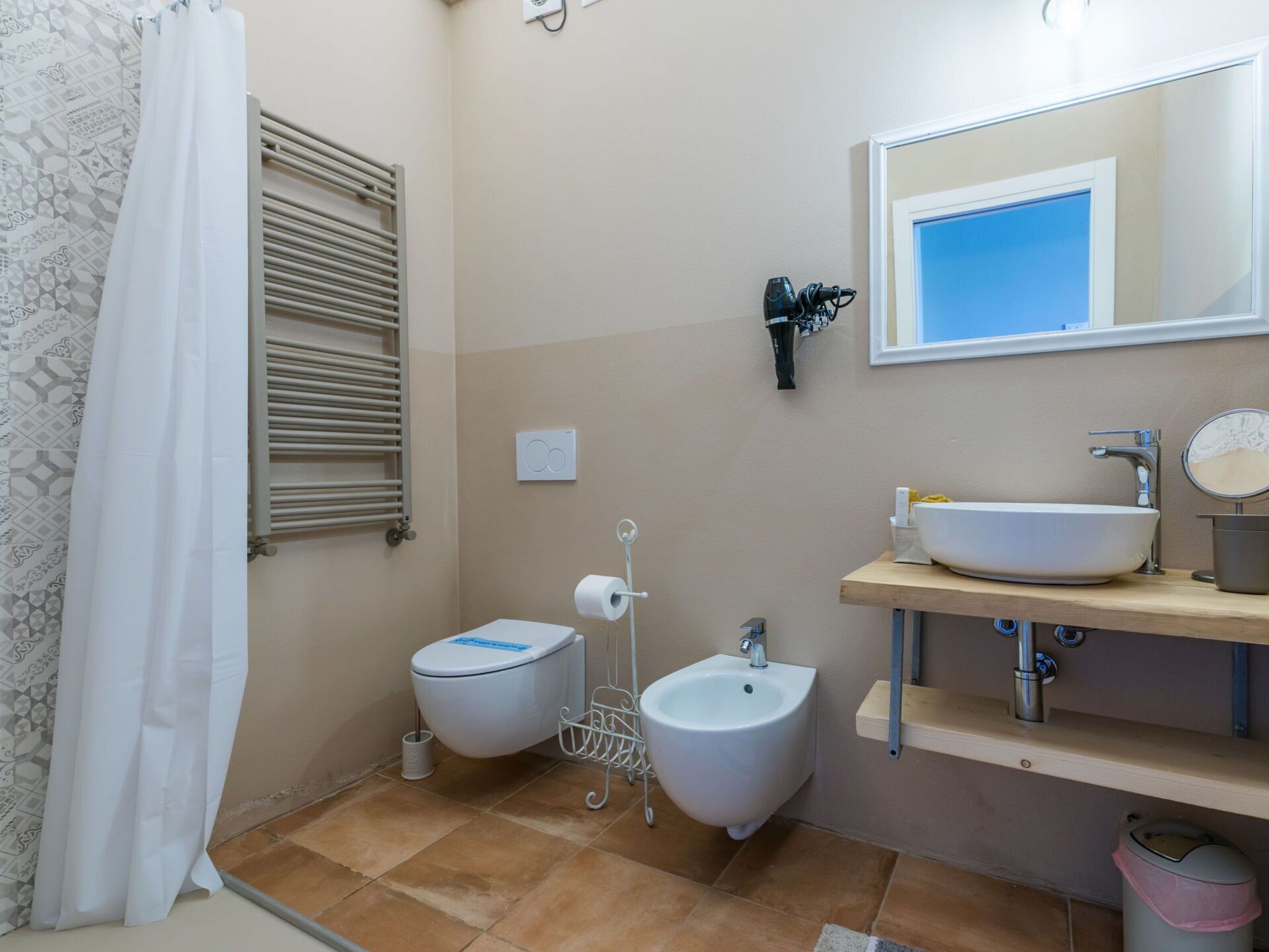 Ein Badezimmer mit Toilette, Bidet, Waschbecken und Spiegel.