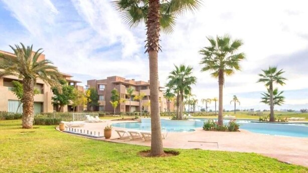 A resort with a swimming pool, palm trees, and a building with balconies. - Residence Marrakech Prestigia Golf City 5384 (Marrakech)