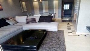 A modern living room with a sofa, coffee table, and a dining area with chairs and a table. - Residence Marrakech Prestigia Golf City 5384 (Marrakech)