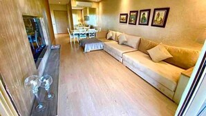 Un salon avec un canapé, un coin repas avec des chaises et une cuisine à l’arrière-plan.
