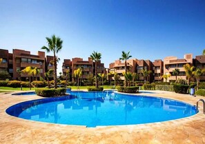 A swimming pool surrounded by palm trees and modern buildings.