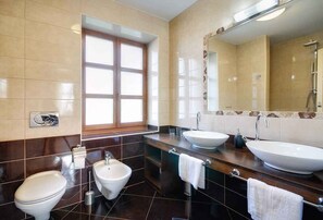 Un baño moderno con dos lavabos, un bidé y un espejo grande.