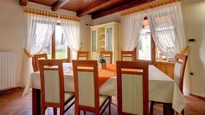 A dining room with a wooden table and chairs, a cabinet, and sheer curtains. - Villa with pool, sauna, sun terrace and WIFI (Golaš)