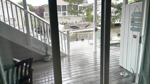 A wooden deck with a glass door leading to a covered outdoor area. - Waterfront 2 Bedroom - 2 Blocks from the Beach - Premium Location (Ocean City)