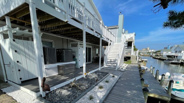 A waterfront property with a covered deck, outdoor seating, and a view of the marina. - Waterfront 2 Bedroom - 2 Blocks from the Beach - Premium Location (Ocean City)