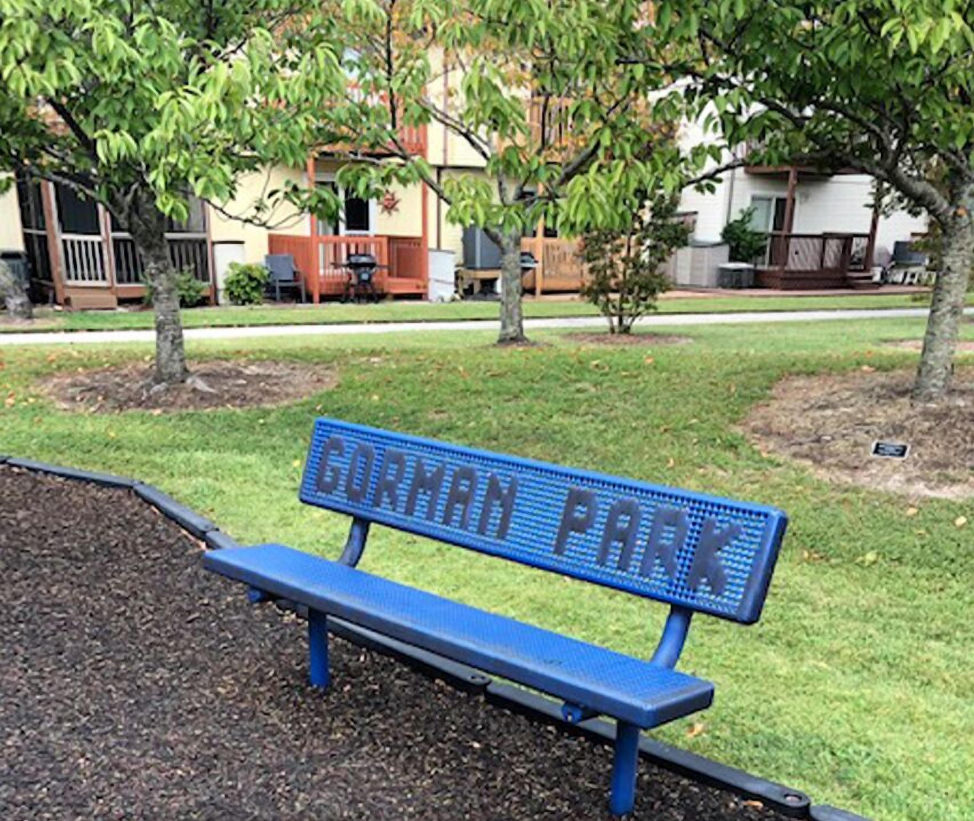 A blue bench with the words "CORMAN PARK" engraved on it.