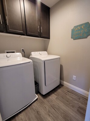 Convenient laundry facilities with two washing machines and storage above.