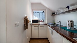 A compact kitchen with a microwave, sink, and a window with curtains. - Apartment "Schnitzer - Enzian" with Mountain View, Wi-Fi, Balcony & Garden (Rabland/Partschins)