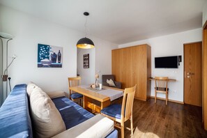 Une pièce moderne comprenant un canapé, une table à manger, des chaises, un téléviseur et des meubles en bois.