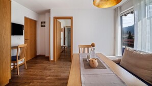 A modern living room with a sofa, a dining table, and a TV. - Apartment "Schnitzer - Enzian" with Mountain View, Wi-Fi, Balcony & Garden (Rabland/Partschins)