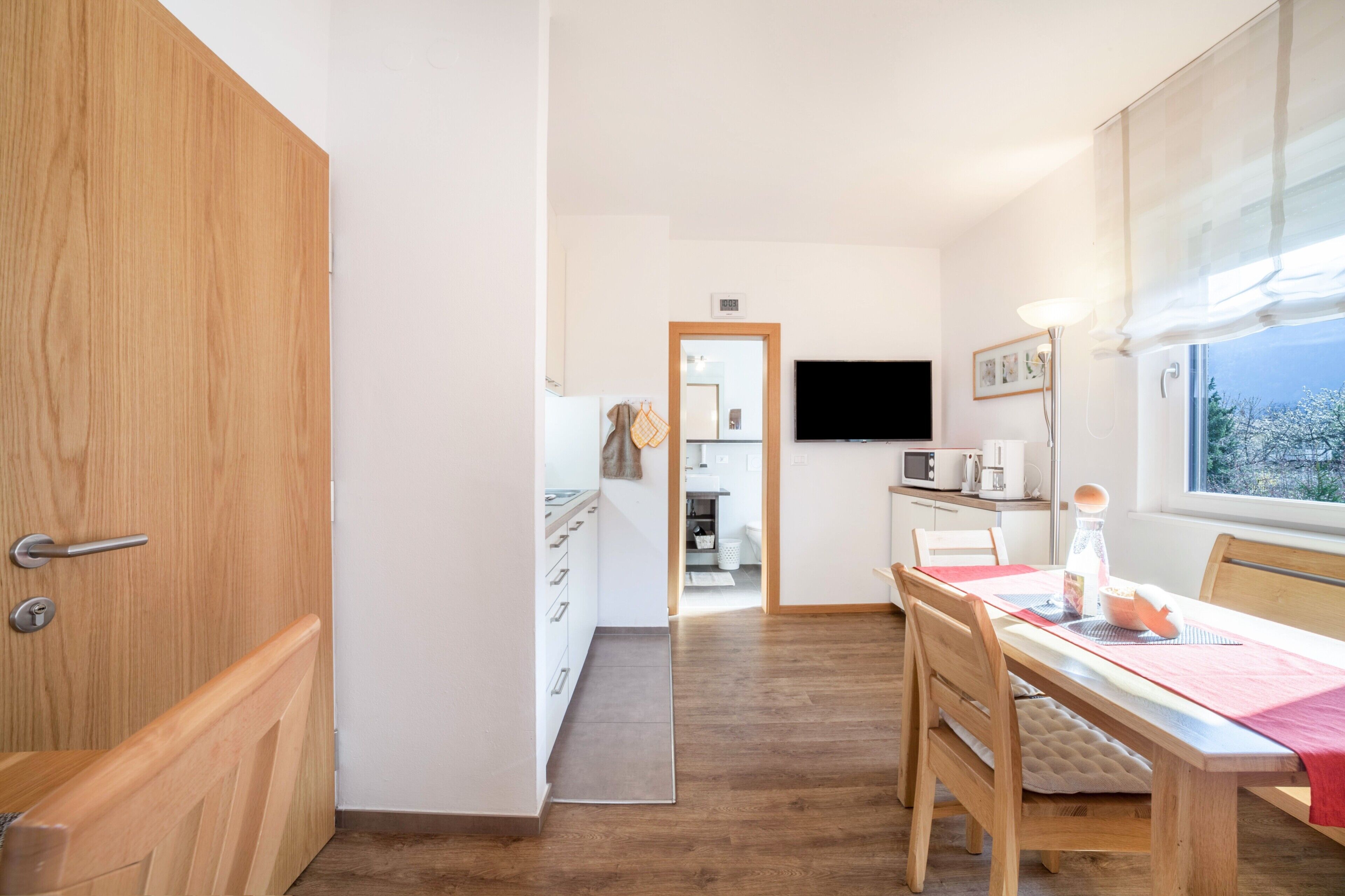 Una cucina moderna con zona pranzo, pavimento in legno e una finestra vista.