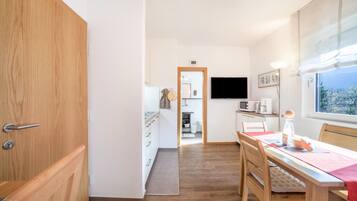 Una cucina moderna con zona pranzo, pavimento in legno e una finestra vista.