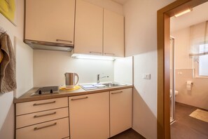 A compact kitchen with a sink, stove, and cabinets.