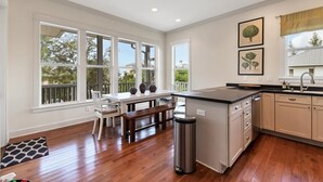 Uma cozinha ampla com grandes janelas, piso de madeira e uma ilha central.
