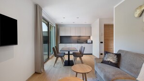 A modern living room with a sofa, a coffee table, and a dining table with chairs. - Premium Apartment Hofer Heidi – Fast Internet, Free Parking (Niederdorf)