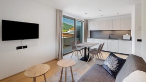 A modern living room with a flat-screen TV, a sofa, a dining table, and chairs. - Premium Apartment Hofer Heidi – Fast Internet, Free Parking (Niederdorf)