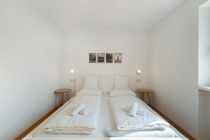 Ein Doppelzimmer mit zwei Betten, Kopfteilen, Nachttischen und drei gerahmten Bildern an der Wand.