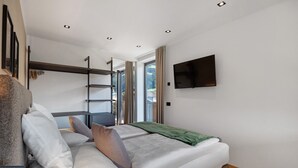 Una habitación moderna con cama, televisión y ventana con cortinas.